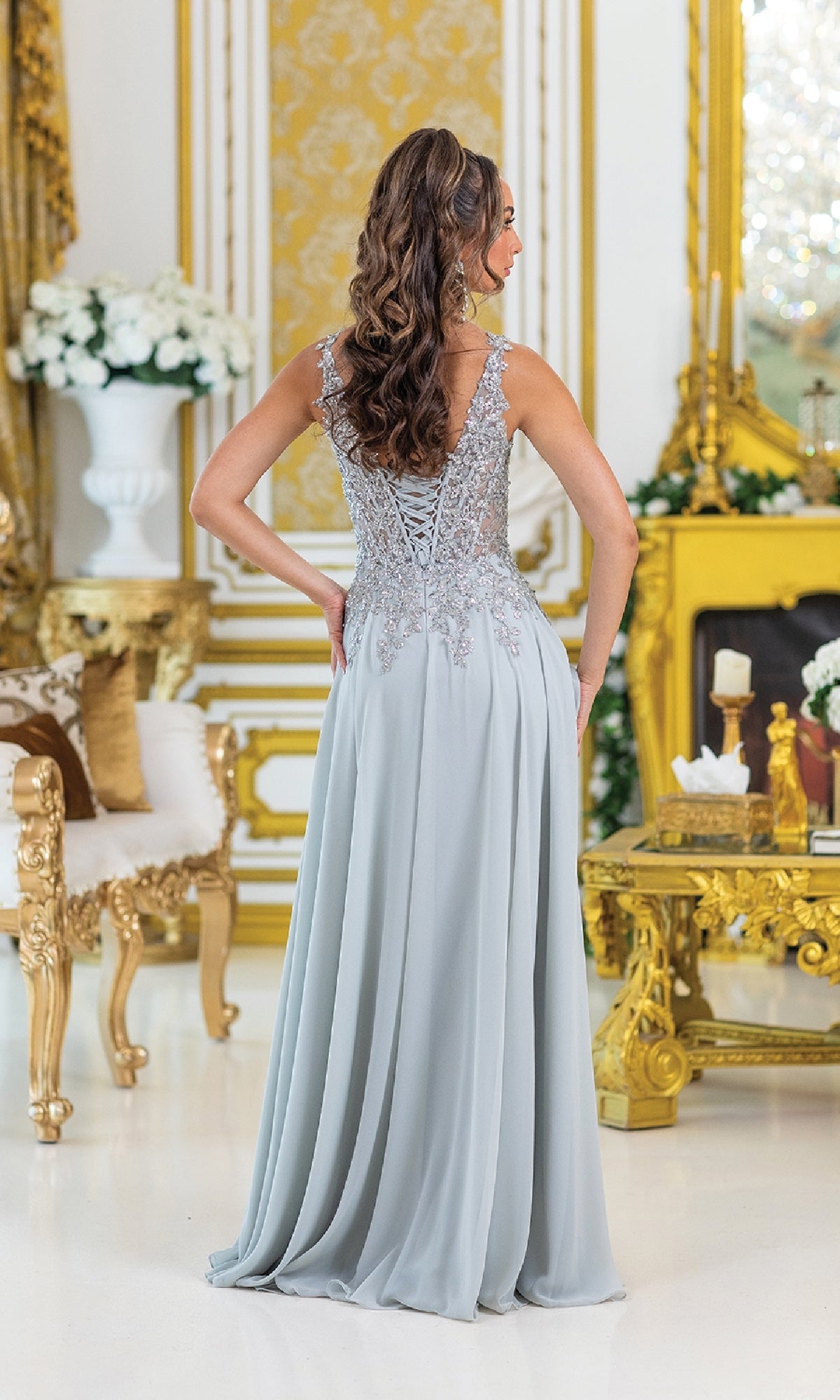 A woman wearing the Lace-Up Long A-Line Prom Dress: Dancing Queen 4446 in light blue stands facing away in an ornate, gold-accented room.